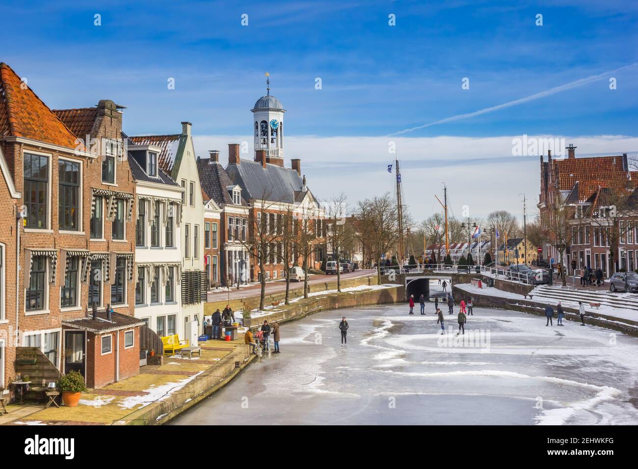 Vecchie case e municipio in un tipico inverno olandese scena con ghiaccio e persone che pattinano Foto Stock