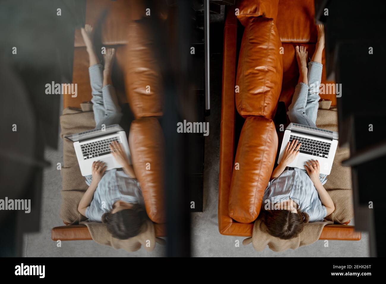 Donna che lavora con un computer portatile da casa su un divano Foto Stock