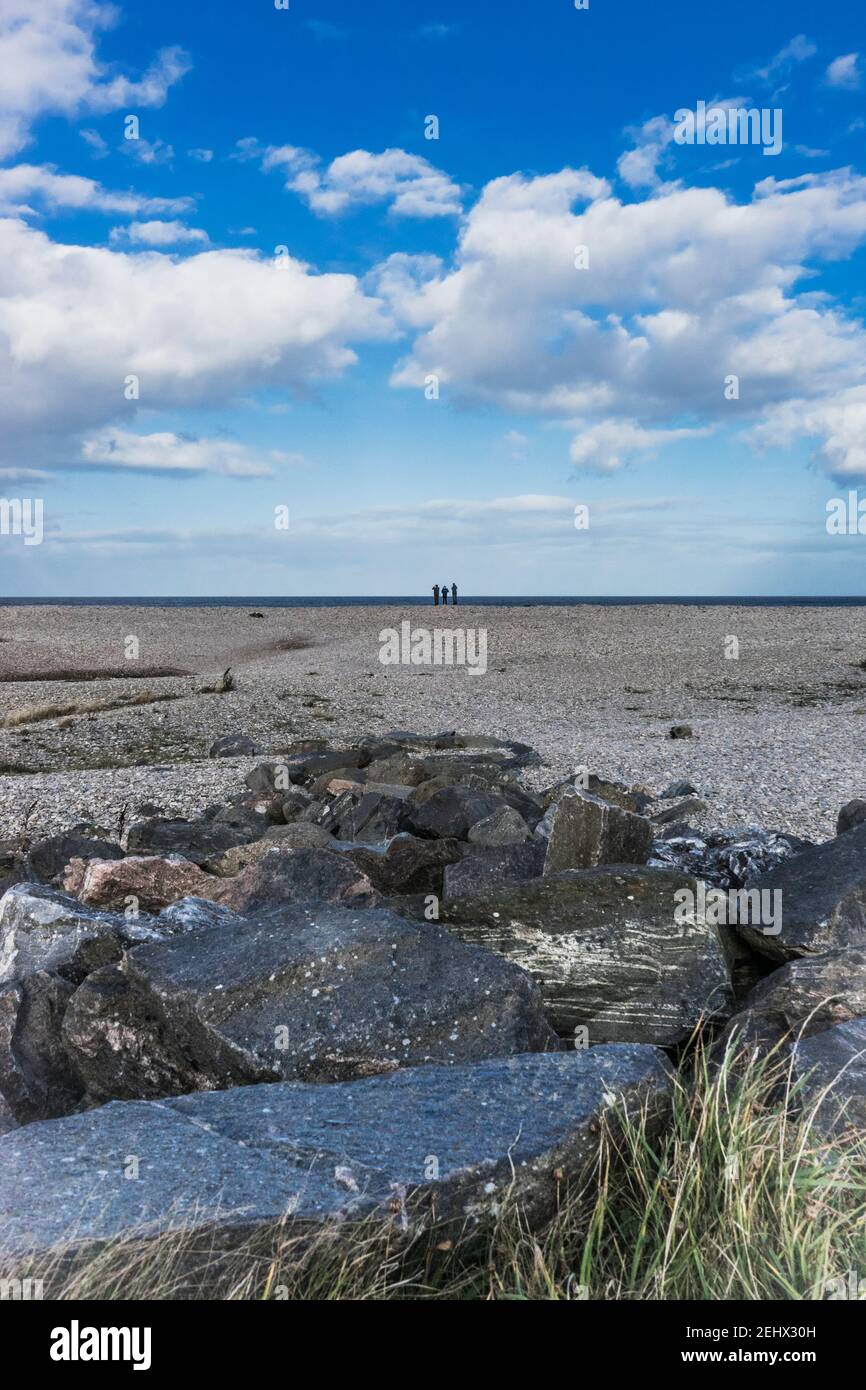 Tre figure all'orizzonte a Spey Bay Scotland Under un cielo blu brillante Foto Stock