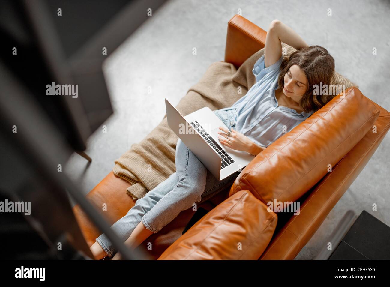 Donna che lavora con un computer portatile da casa su un divano Foto Stock