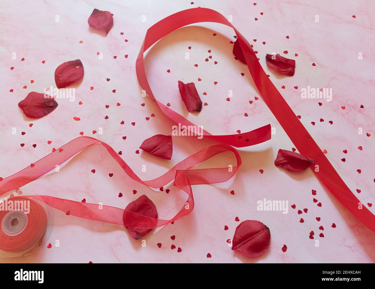 sfondo in marmo rosa con ornamenti da regalo cuori e rosa petali Foto Stock
