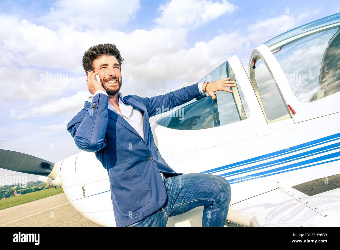 Giovane bell'uomo che parla con lo smartphone al privato Aereo: Concetto aziendale moderno con un ragazzo sicuro che utilizza lo smartphone in aeroporto Foto Stock