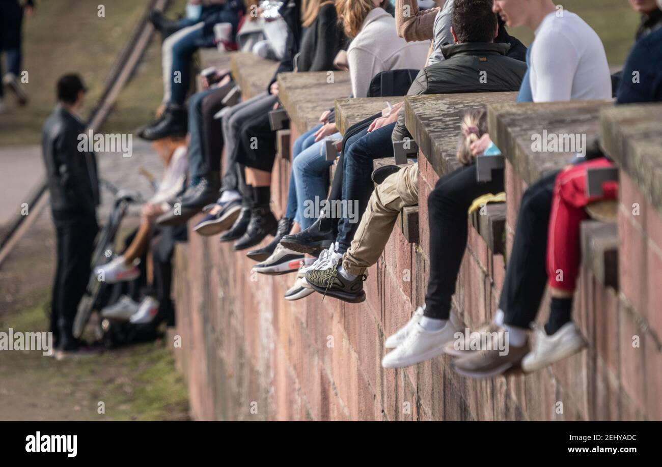 20 febbraio 2021, Hessen, Francoforte sul meno: Numerosi escursionisti si siedono sull'alta banchina al sole sulle rive del meno a Francoforte nel pomeriggio e lasciano le gambe sgranchirsi. Foto: Frank Rumpenhorst/dpa Foto Stock