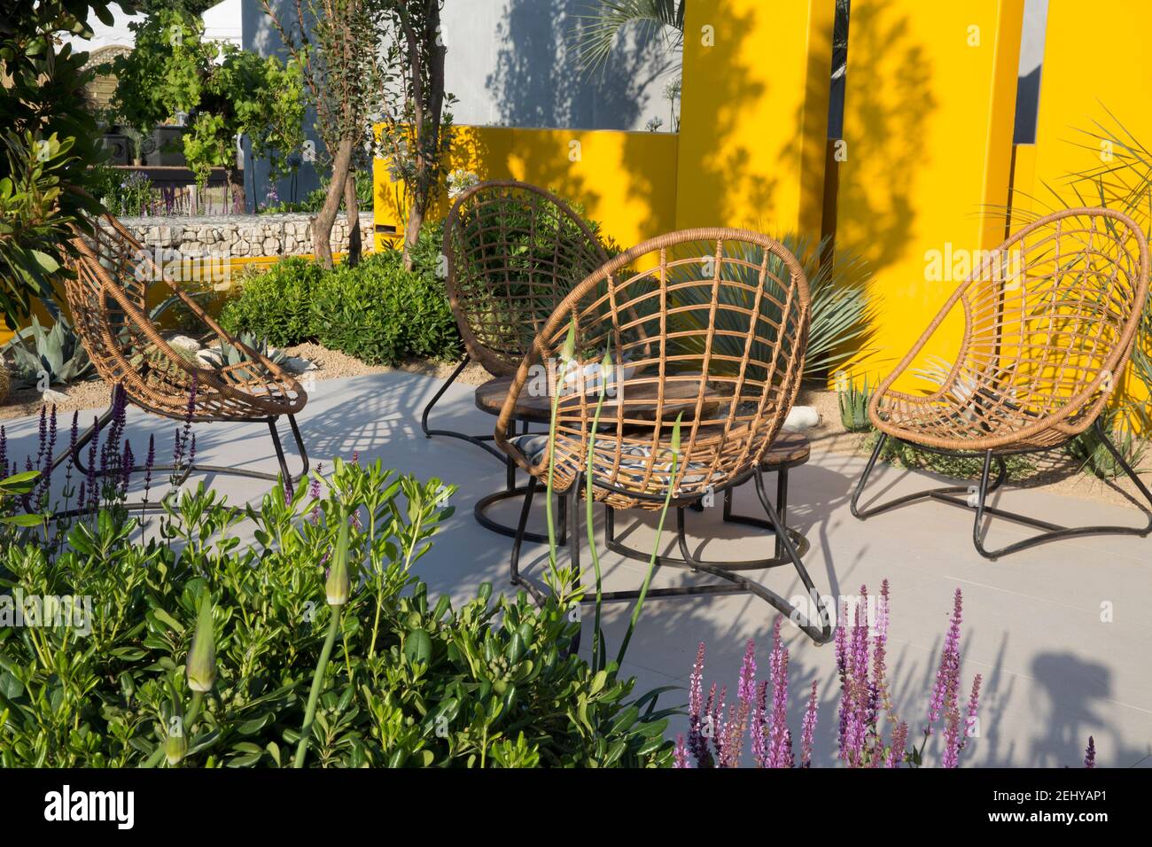 Giardino moderno design Mediterraneo clima giardino moderno grigio pietra pavimentata patio area salotto tavolo in rattan e sedie di canna su una terrazza Hampton Foto Stock