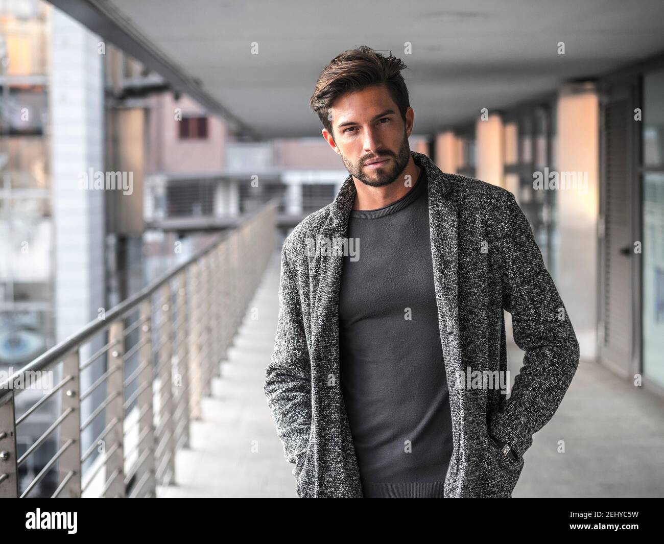Un attraente uomo in ambiente cittadino indossa cardigan Foto Stock