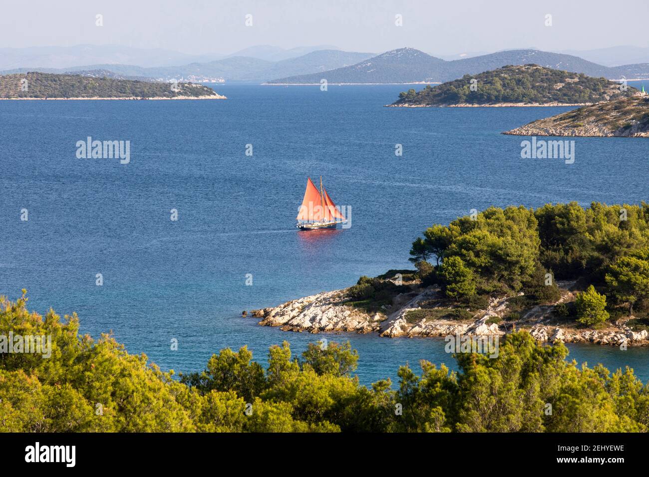 una barca a vela con vele rosse naviga sul mare Foto Stock