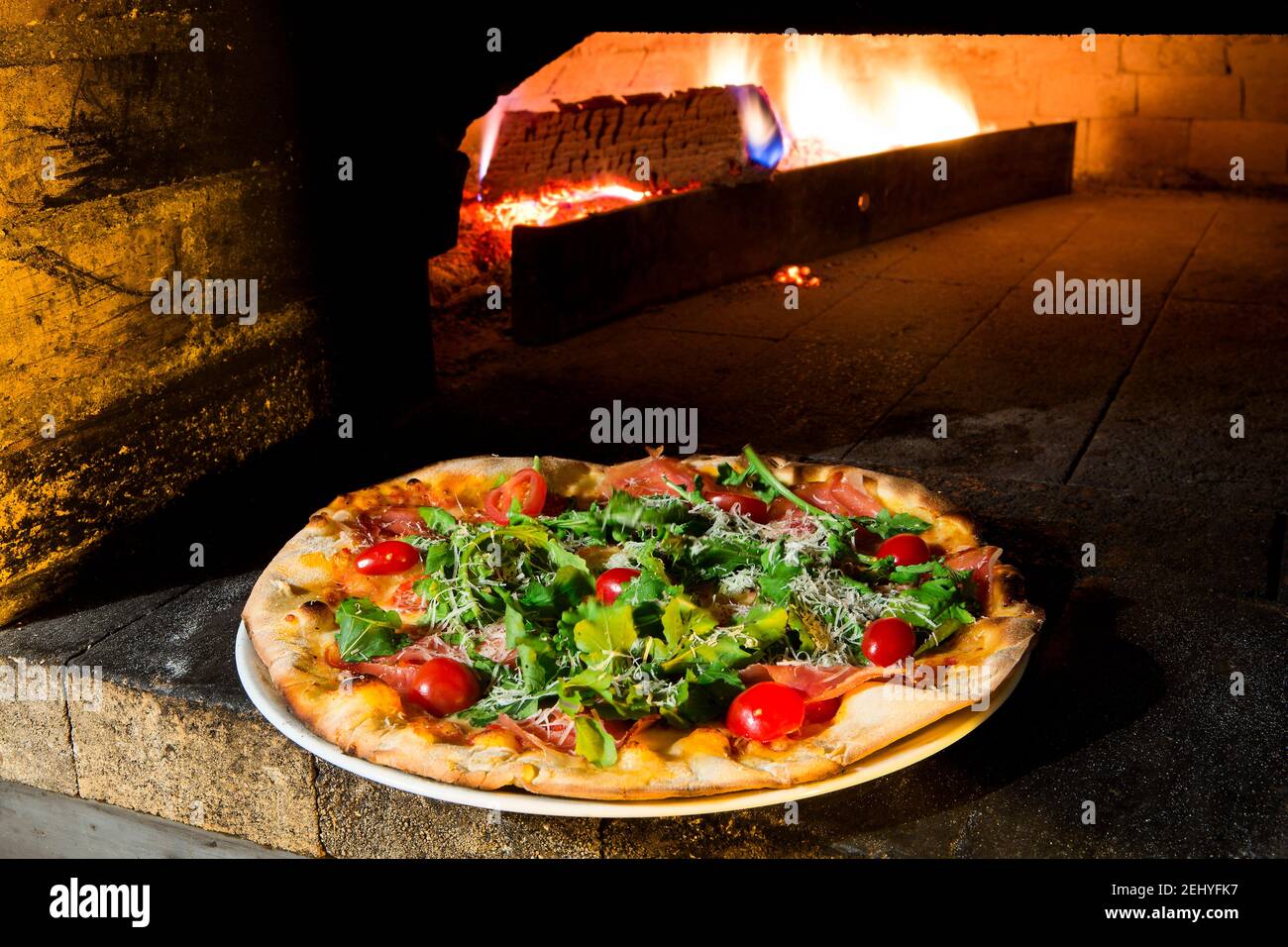 Pane forno Pizza con Arugula, pomodori e pancetta. Foto Stock