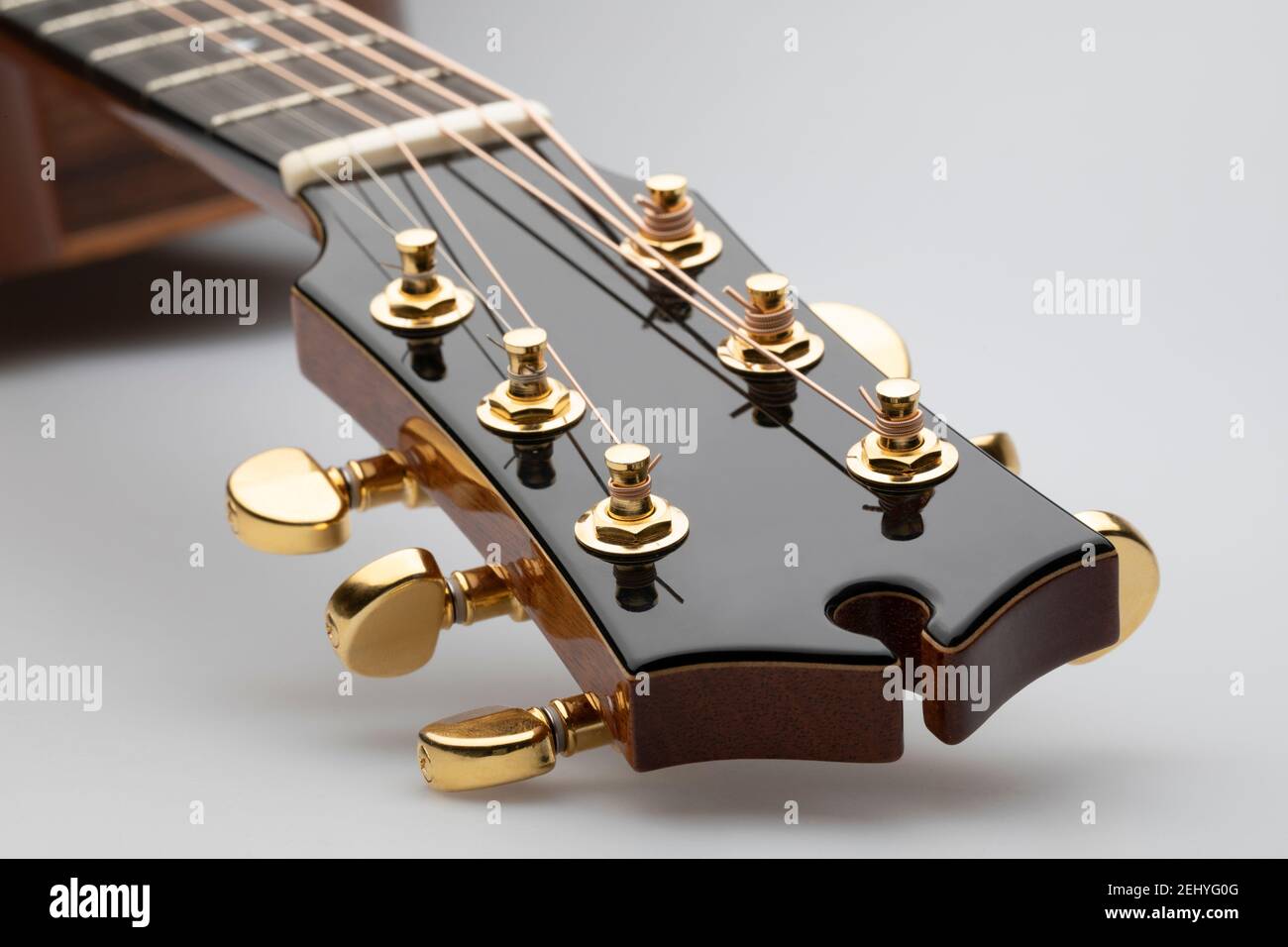 Primo piano di una testa di chitarra acustica con i tasti di sintonizzazione su sfondo bianco Foto Stock