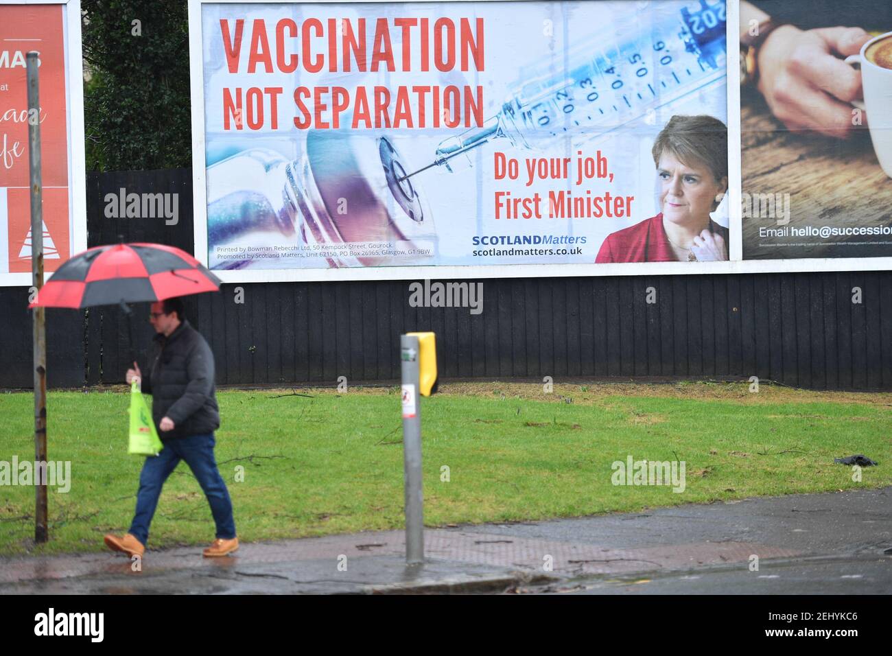 Greenock, Scozia, Regno Unito. 20 febbraio 2021. Nella foto: Immagine del primo ministro scozzese Nicola Sturgeon con la grafica di un vaccino COVID19 e una siringa con lo slogan: "VACCINAZIONE NON SEPARAZIONE. FAI IL TUO LAVORO, PRIMO MINISTRO." su un cartellone nel mezzo di Greenock, in un crocevia trafficato di Brougham St & Campbell St. Questo è in riferimento alla maggioranza silenziosa di persone in Scozia che si oppongono alla SNP cercando un secondo referendum sull'indipendenza nel mezzo di una pandemia che lo ha fatto Nel Regno Unito sono state uccise oltre 106,000 persone, di cui 6,816 nella sola Scozia. Credit: Colin Fisher/Alamy Live News. Foto Stock