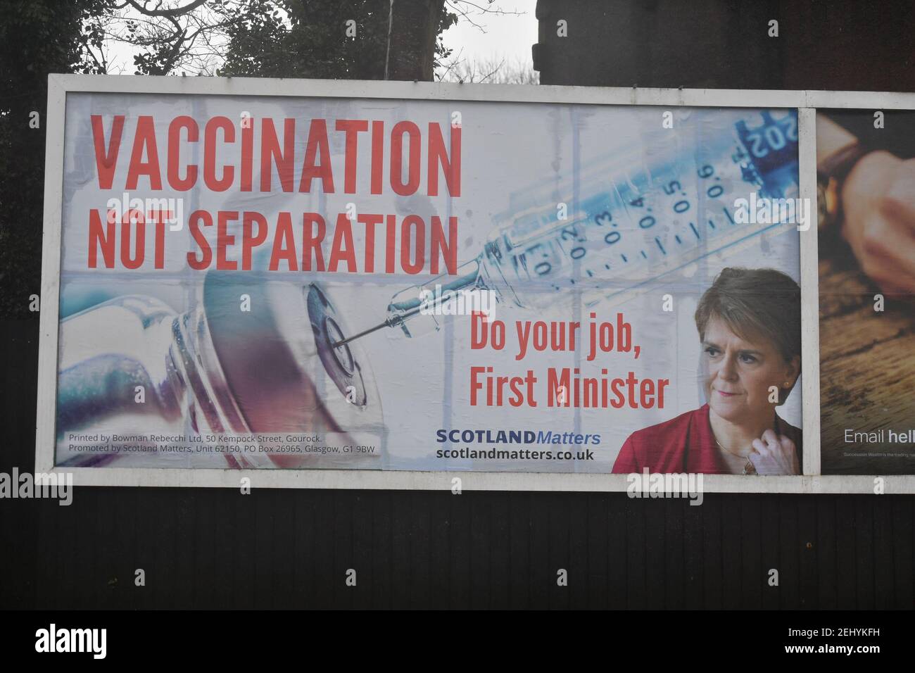 Greenock, Scozia, Regno Unito. 20 febbraio 2021. Nella foto: Immagine del primo ministro scozzese Nicola Sturgeon con la grafica di un vaccino COVID19 e una siringa con lo slogan: "VACCINAZIONE NON SEPARAZIONE. FAI IL TUO LAVORO, PRIMO MINISTRO." su un cartellone nel mezzo di Greenock, in un crocevia trafficato di Brougham St & Campbell St. Questo è in riferimento alla maggioranza silenziosa di persone in Scozia che si oppongono alla SNP cercando un secondo referendum sull'indipendenza nel mezzo di una pandemia che lo ha fatto Nel Regno Unito sono state uccise oltre 106,000 persone, di cui 6,816 nella sola Scozia. Credit: Colin Fisher/Alamy Live News. Foto Stock