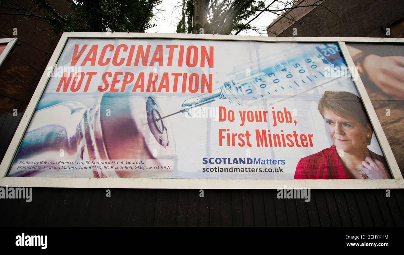 Greenock, Scozia, Regno Unito. 20 febbraio 2021. Nella foto: Immagine del primo ministro scozzese Nicola Sturgeon con la grafica di un vaccino COVID19 e una siringa con lo slogan: "VACCINAZIONE NON SEPARAZIONE. FAI IL TUO LAVORO, PRIMO MINISTRO." su un cartellone nel mezzo di Greenock, in un crocevia trafficato di Brougham St & Campbell St. Questo è in riferimento alla maggioranza silenziosa di persone in Scozia che si oppongono alla SNP cercando un secondo referendum sull'indipendenza nel mezzo di una pandemia che lo ha fatto Nel Regno Unito sono state uccise oltre 106,000 persone, di cui 6,816 nella sola Scozia. Credit: Colin Fisher/Alamy Live News. Foto Stock
