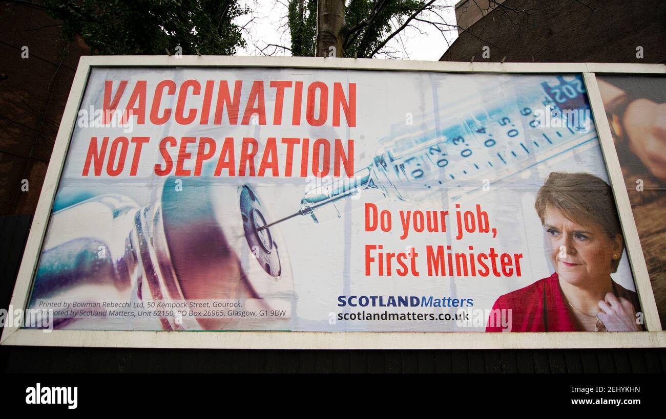 Greenock, Scozia, Regno Unito. 20 febbraio 2021. Nella foto: Immagine del primo ministro scozzese Nicola Sturgeon con la grafica di un vaccino COVID19 e una siringa con lo slogan: "VACCINAZIONE NON SEPARAZIONE. FAI IL TUO LAVORO, PRIMO MINISTRO." su un cartellone nel mezzo di Greenock, in un crocevia trafficato di Brougham St & Campbell St. Questo è in riferimento alla maggioranza silenziosa di persone in Scozia che si oppongono alla SNP cercando un secondo referendum sull'indipendenza nel mezzo di una pandemia che lo ha fatto Nel Regno Unito sono state uccise oltre 106,000 persone, di cui 6,816 nella sola Scozia. Credit: Colin Fisher/Alamy Live News. Foto Stock