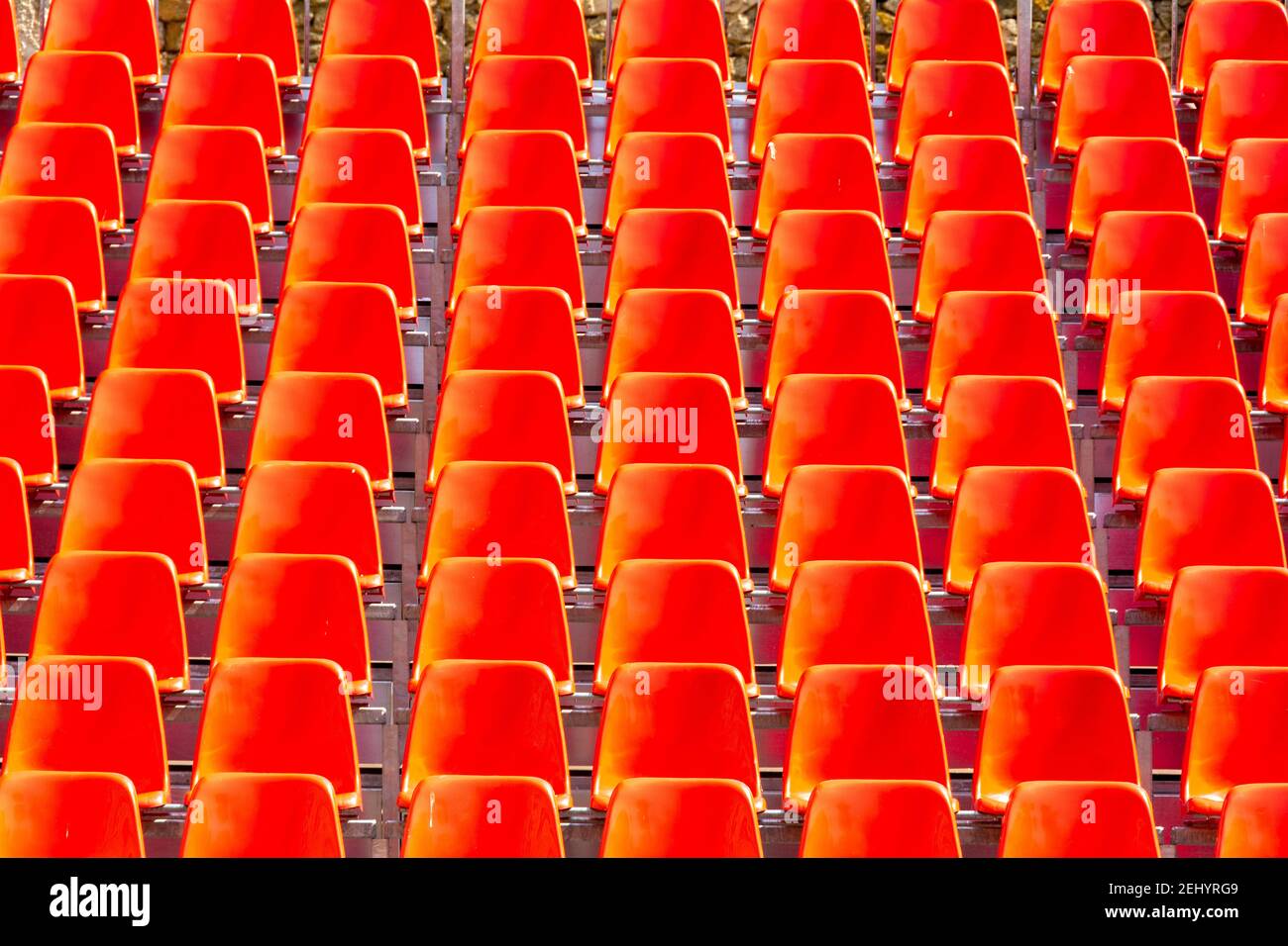 File di vivaci sedie rosse disposte in perfetto allineamento per un evento imminente in un luogo moderno Foto Stock