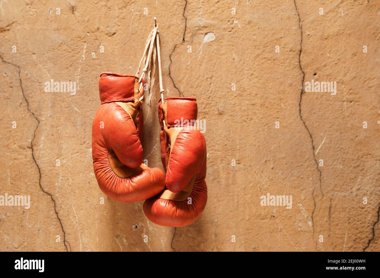 Vecchi guanti da boxe appesi su una parete incrinata, che mostrano un senso di nostalgia e lo spirito di questo sport Foto Stock