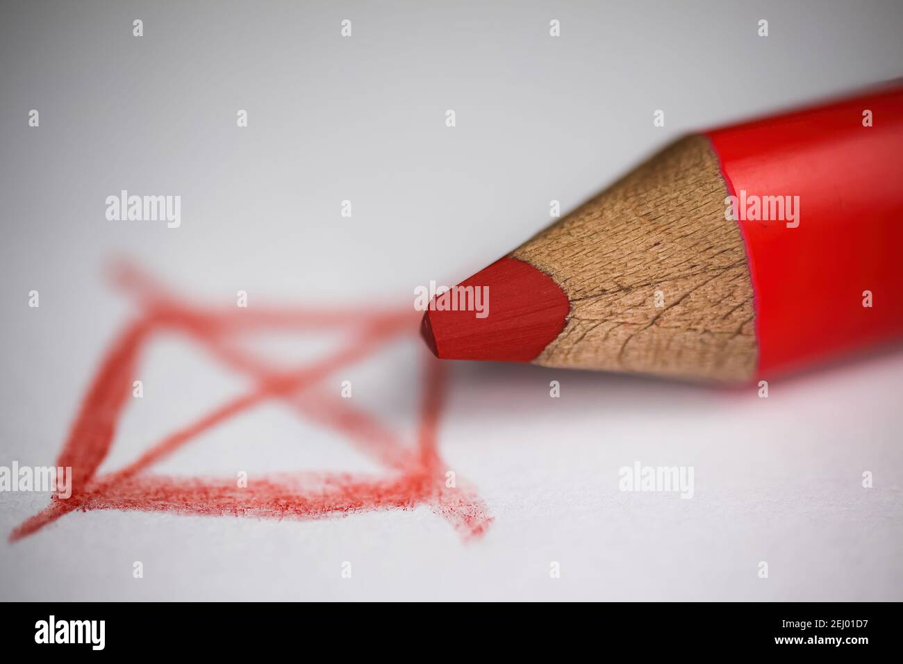 Makro primo piano della relativa scatola rossa con il contrassegno a croce, pastello di legno su sfondo di carta bianca (messa a fuoco sulla punta della matita) Foto Stock