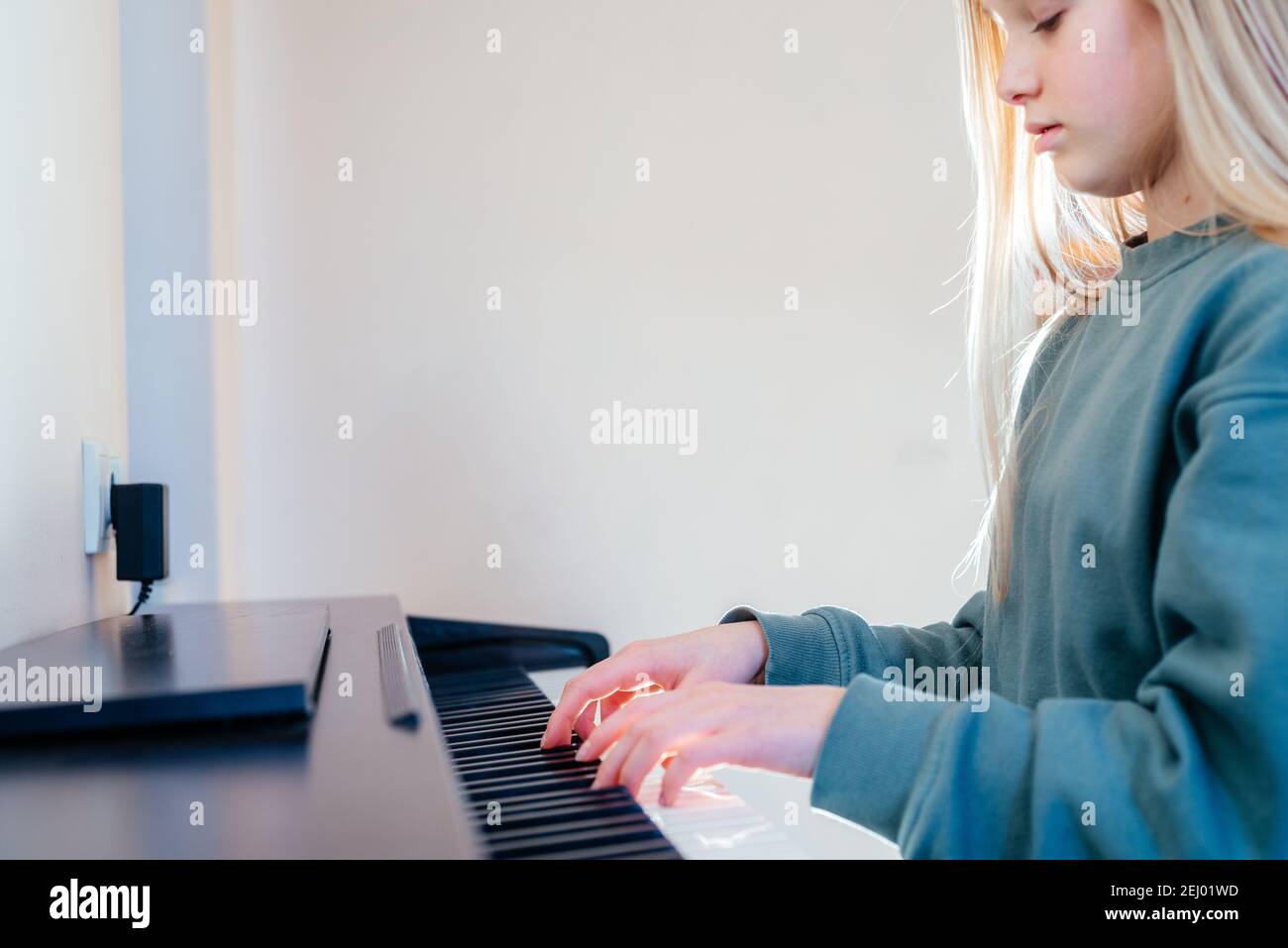 Una ragazza adolescente che suona un pianoforte elettrico a casa Foto Stock