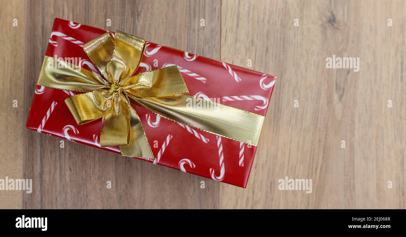 carta rossa regalo di natale e nastro d'oro con sfondo in legno Foto Stock