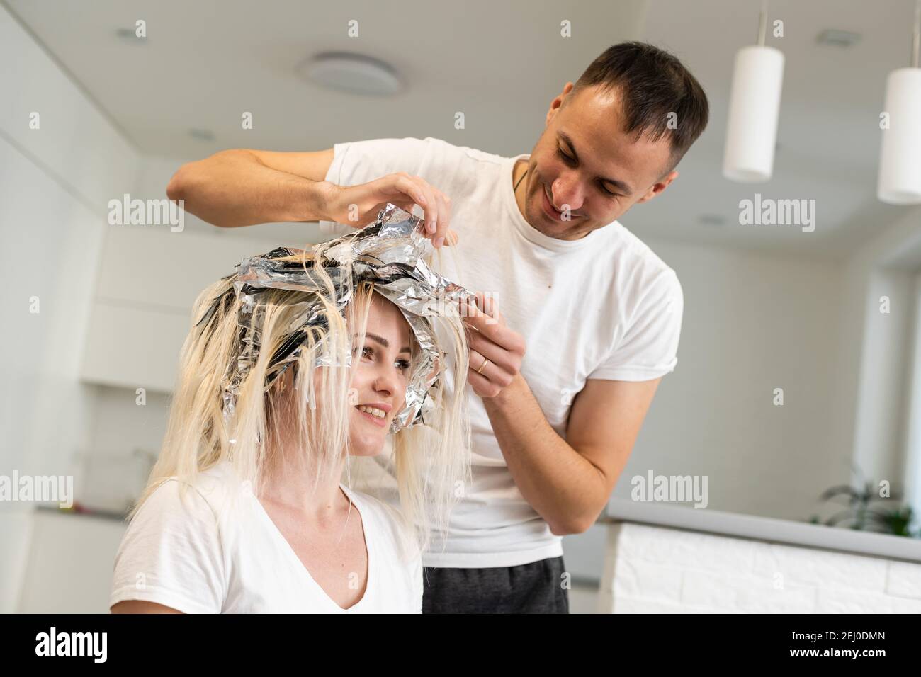 Sorridente stilista sta morendo capelli lunghi, uomo parrucchiere tintura  donna capelli Foto stock - Alamy