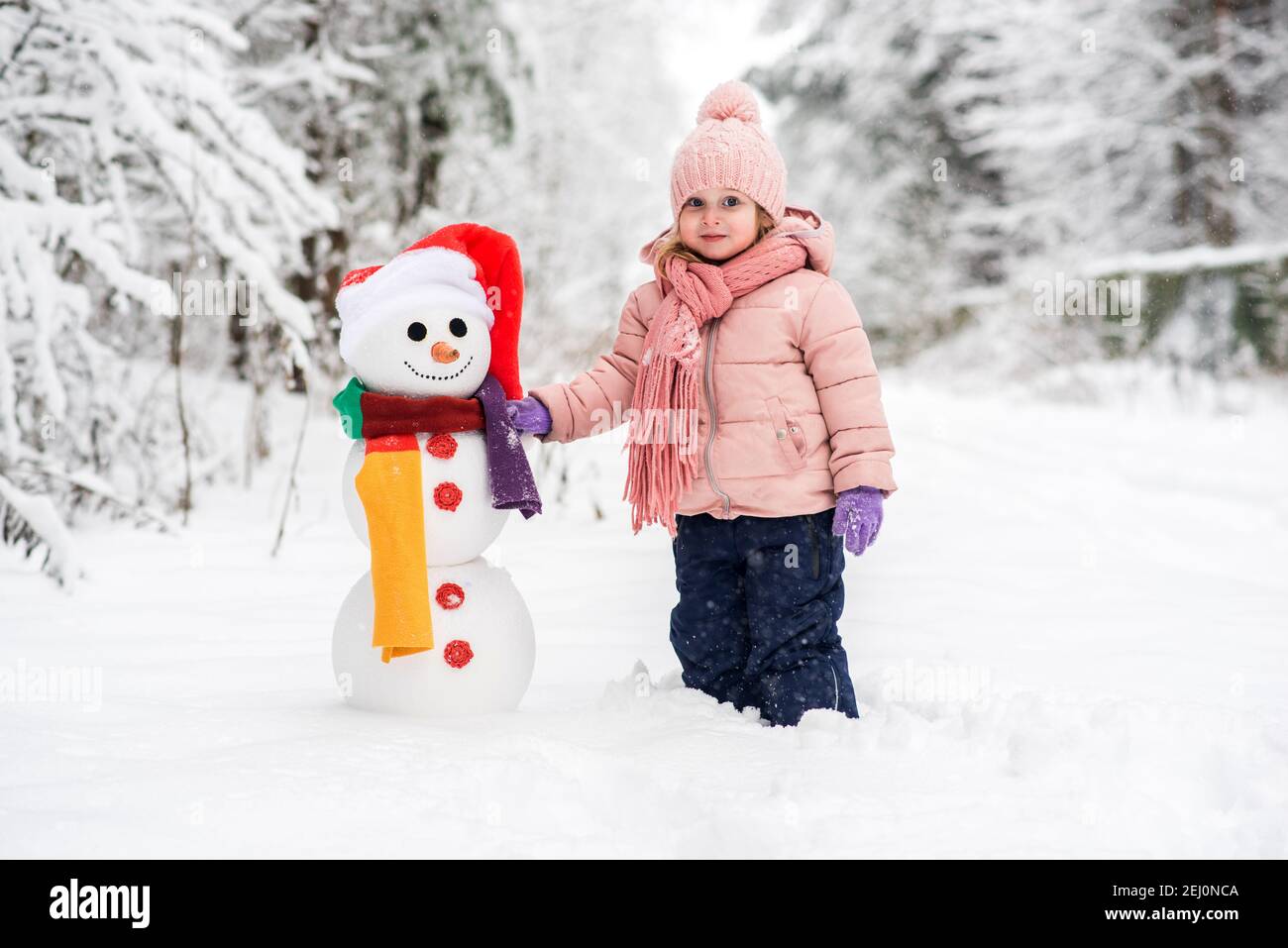 Carino ragazzo e ragazza costruire pupazzo di neve nella foresta invernale Foto Stock