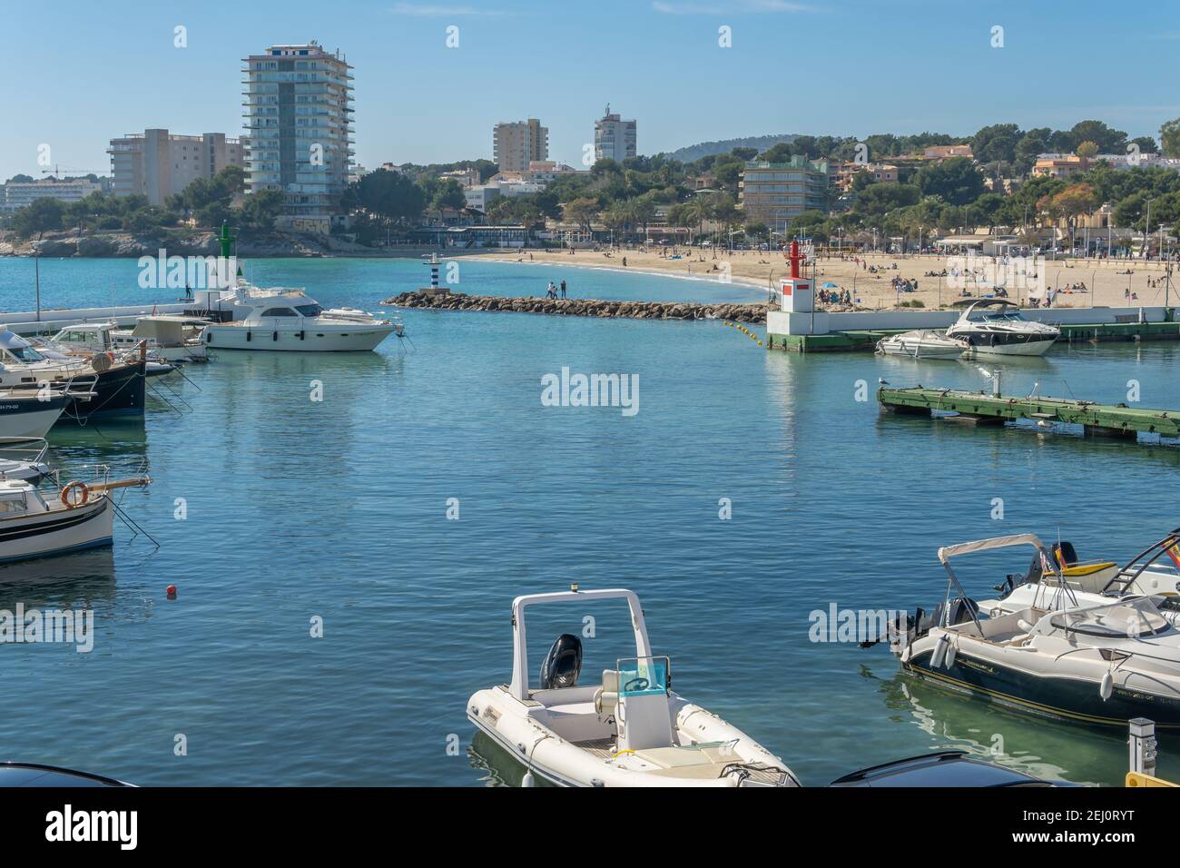 Palmanova, Spagna; febbraio 20 2021: Vista generale del porto turistico e della spiaggia della località di Palmanova in una giornata di sole, con le famiglie che si godono t Foto Stock