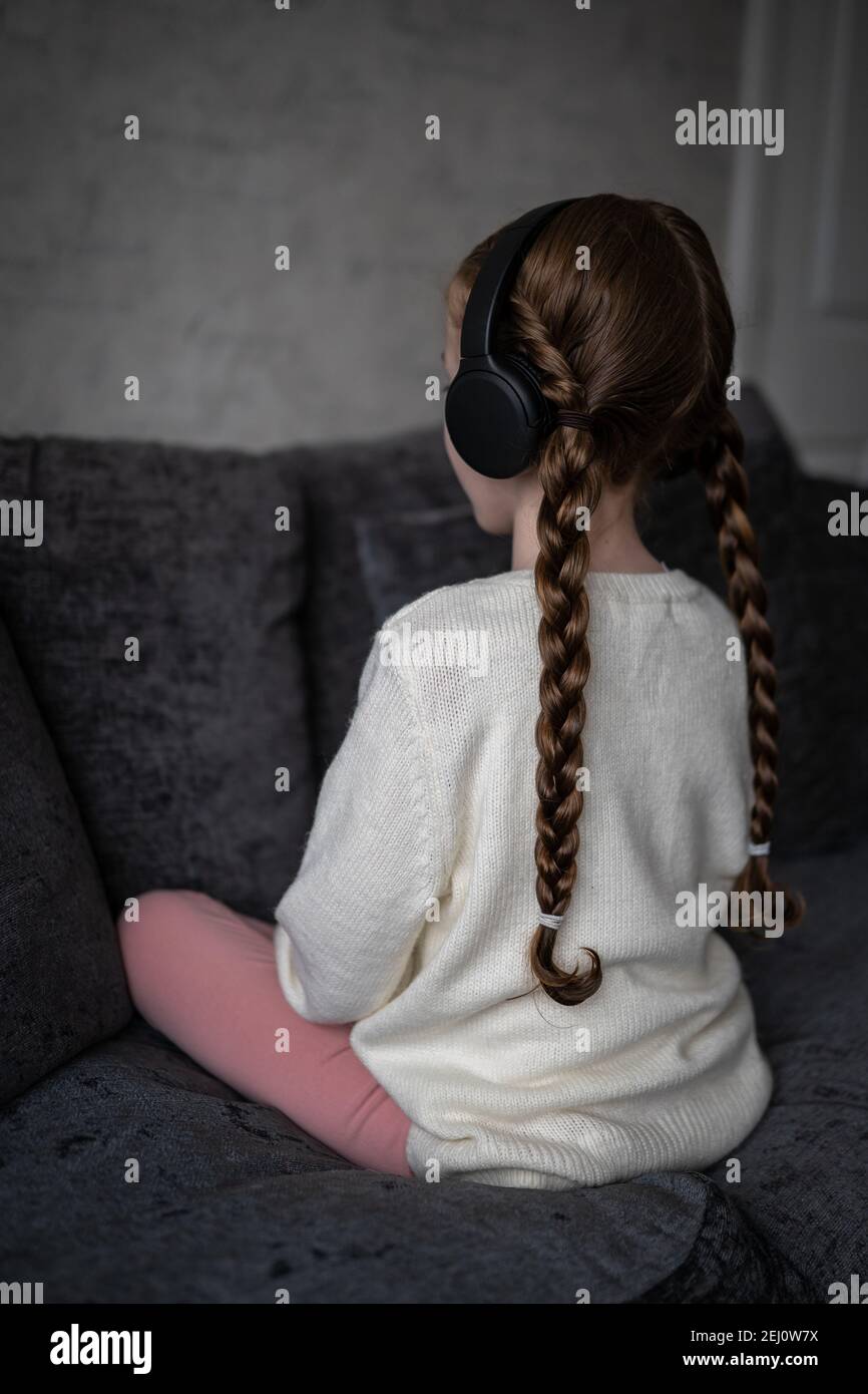 Spettro autistico giovane ragazza seduta tranquilla e da sola con autismo guardando indietro, l'ansia e le cuffie si sono attivate per bloccarle rumore esterno che causa distress Foto Stock