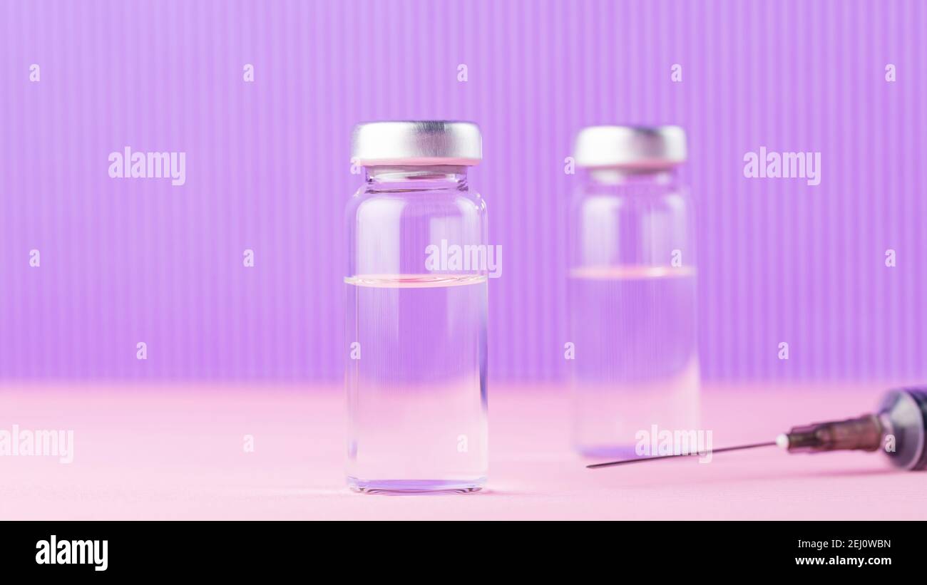 Vaccini e siringhe su sfondo viola rosa per la prevenzione e l'immunizzazione. Iniezione di vaccino e siringa. Concetto medico. Spazio di copia Foto Stock