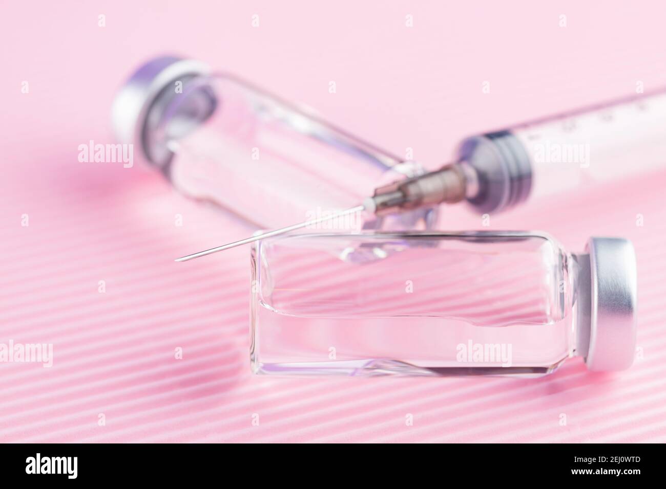 Concetto di cura sanitaria con iniezione di vaccino e siringa. Vaccini e siringhe su sfondo rosa per la prevenzione e l'immunizzazione. Spazio di copia. In alto Foto Stock