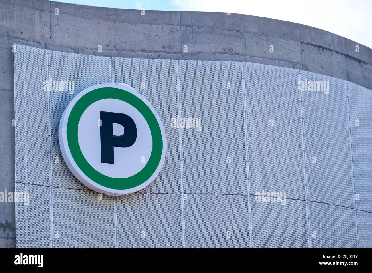 Un cartello con la scritta "P" indica il parcheggio pubblico dove è appeso al muro di un garage in cemento. Foto Stock