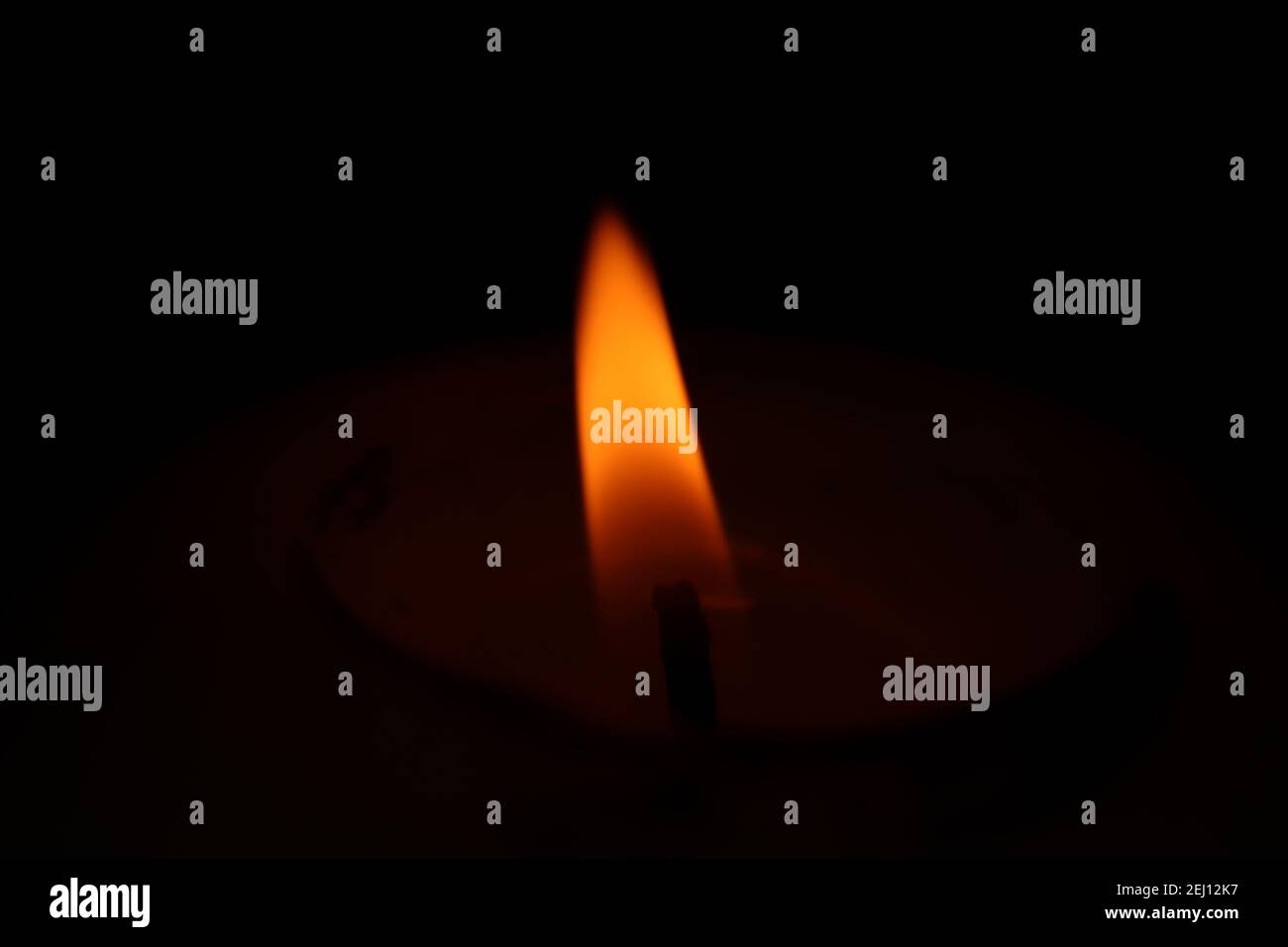 Una candela luminosa a bassa luminosità al buio che crea un umore triste e cordognoso. Foto Stock