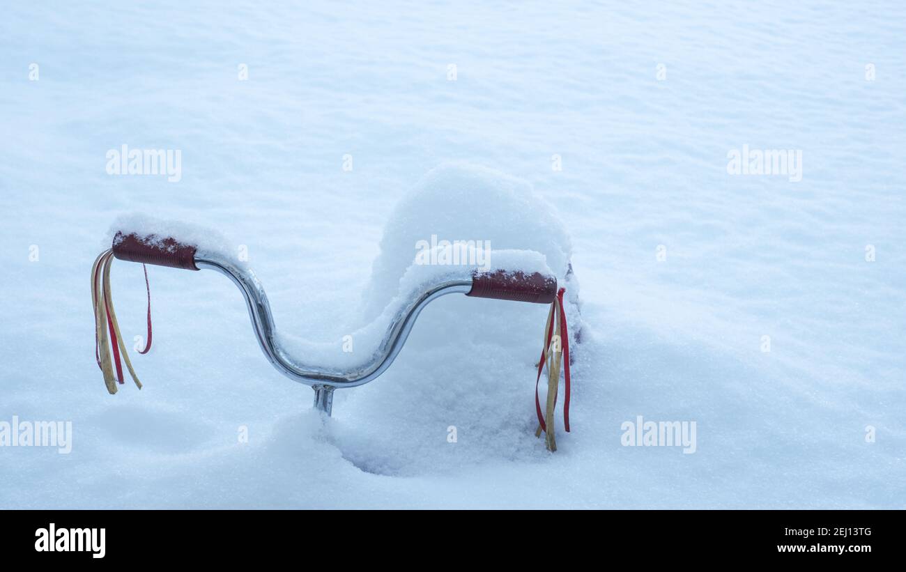 Un triciclo rosso con ruscelli del manubrio è quasi sepolto nella neve profonda dopo una nevicata pesante. Foto Stock