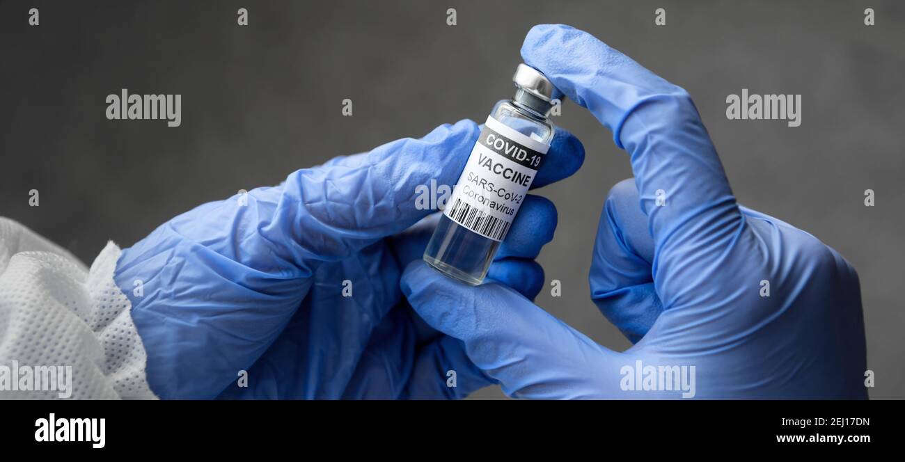 Vaccino del coronavirus nelle mani del medico, banner panoramico con il medico che tiene una bottiglia di vaccino COVID-19. Concetto di salute, cura del virus corona, va Foto Stock