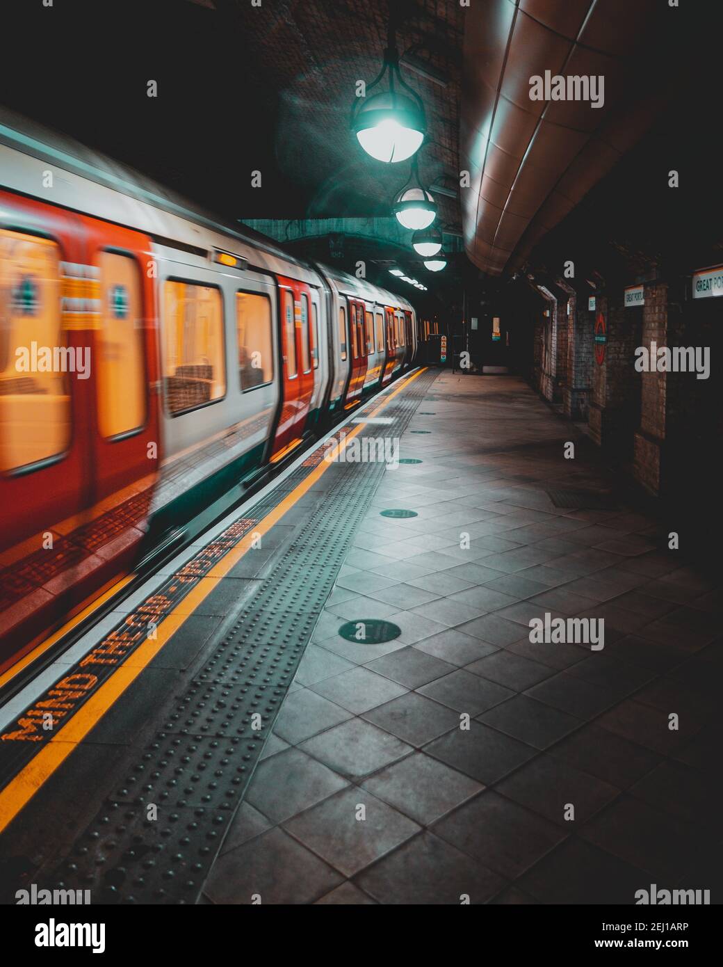 Londra UK Gennaio 2021 Londra Metropolitana metropolitana in avvicinamento alla piattaforma della stazione, sfocata in movimento con lunga esposizione. Scatto verticale di una moodia scura Foto Stock