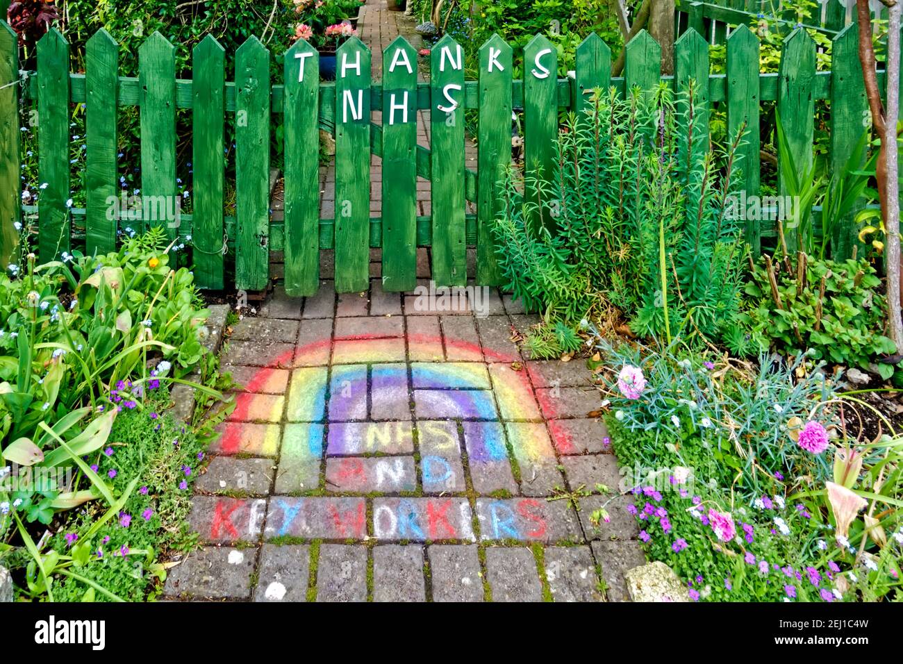 Warminster, Wiltshire UK - 5 maggio 2020: Un ringraziamento NHS e lavoratori chiave Arcobaleno di speranza su un percorso giardino e cancello di una casa Foto Stock