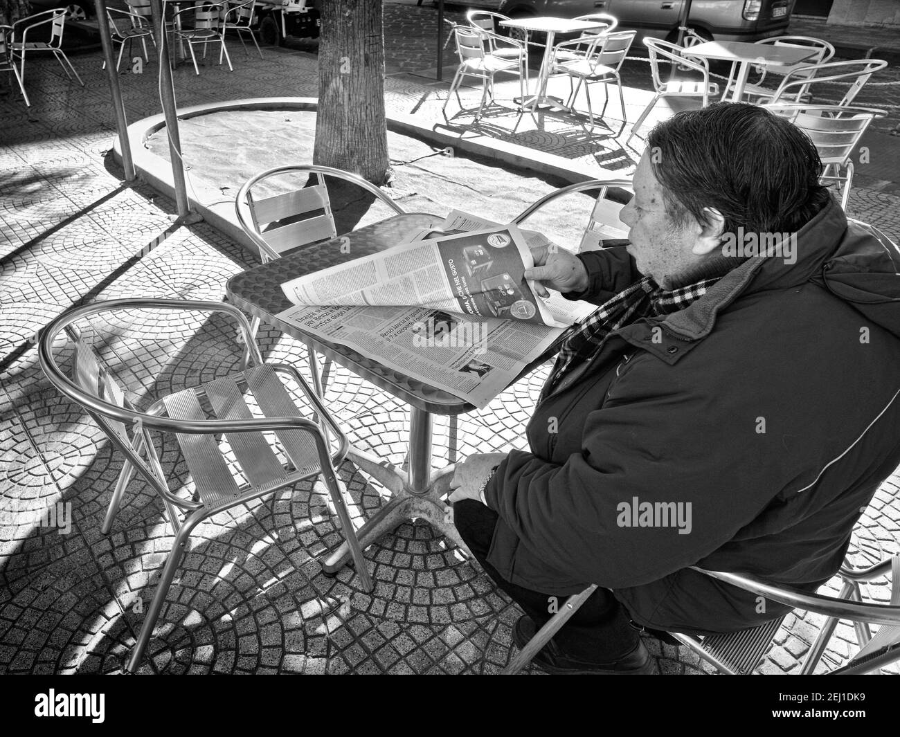 SIRACUSA, ITALIA - JENARY 03: Un uomo con un sigaro è seduto in un caffè all'aperto e sta leggendo un giornale. Girato nel 2015 Foto Stock