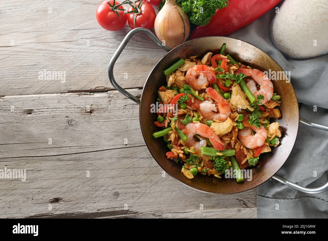 Paella, piatto di riso della Spagna con gamberi, pollo e verdure in una padella piatta su un tavolo rustico in legno, spazio copia, alto angolo vista dall'alto Foto Stock