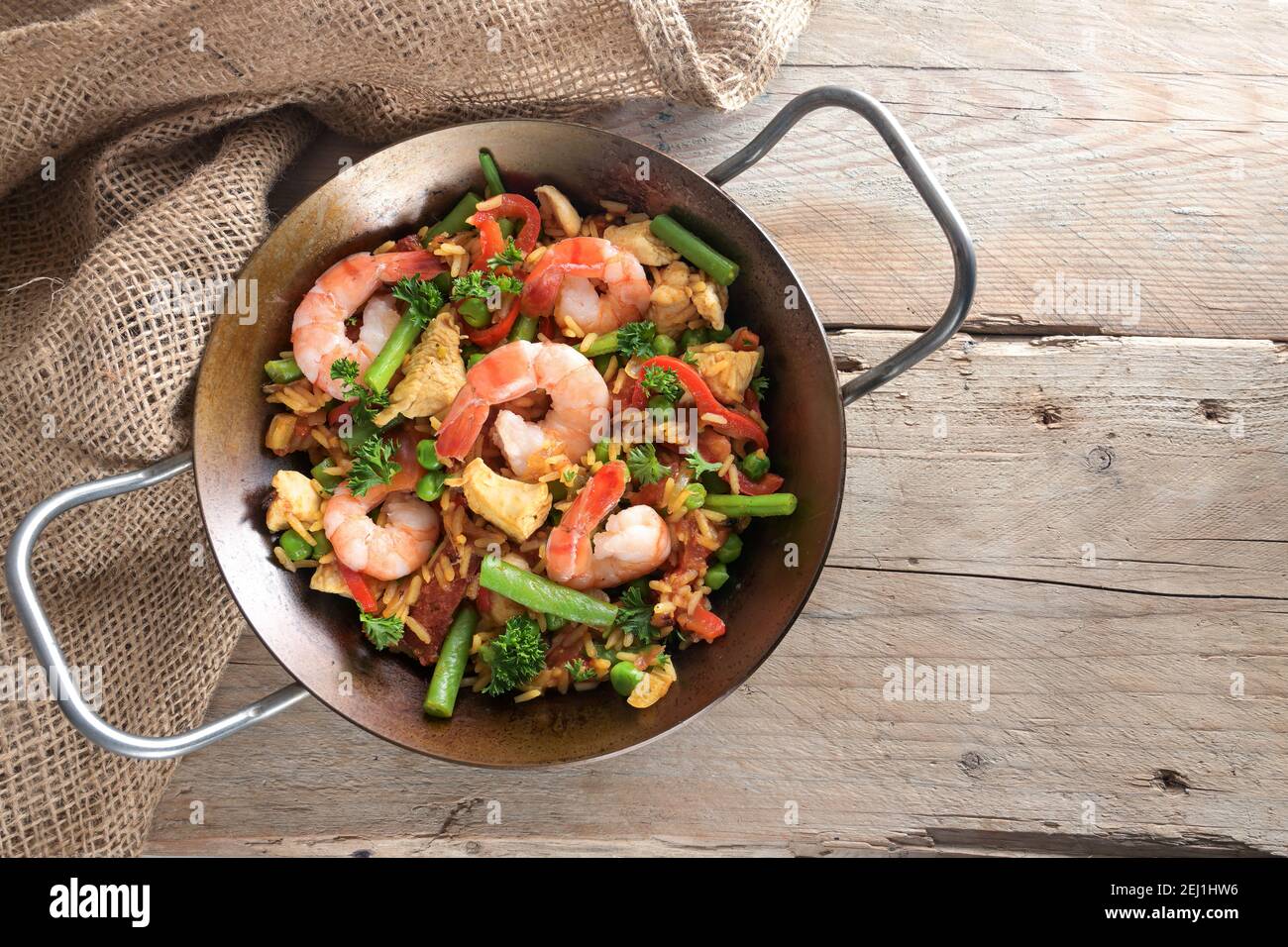 Piatto di riso fatto in casa con frutti di mare, pollo e verdure in una paella paella su tavole rustiche in legno, spazio copia, vista dall'alto dell'angelo Foto Stock
