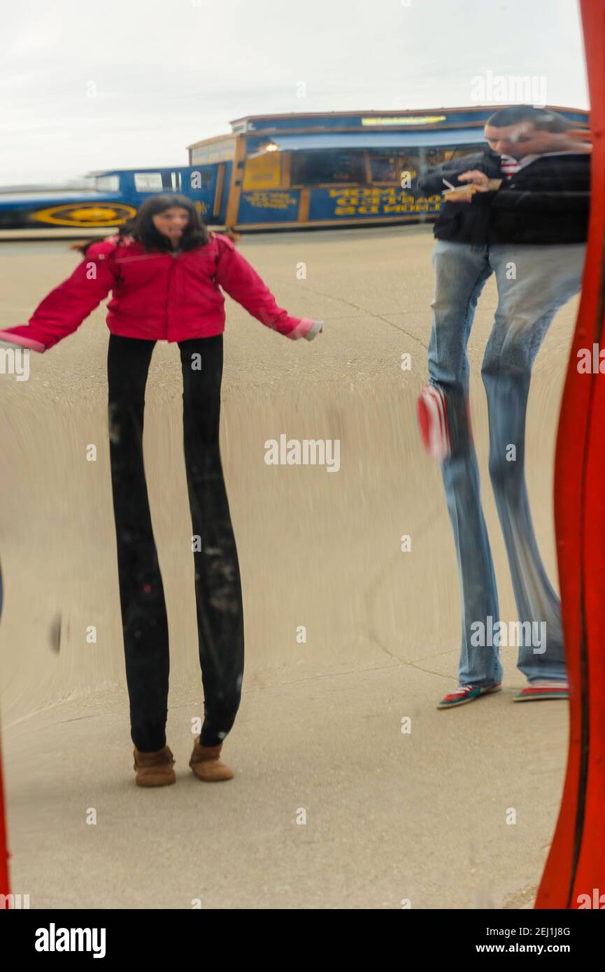 L'immagine a specchio di una giovane ragazza che indossa una giacca rossa si riflette sulla superficie di uno specchio distorsivo al Navy Pier, Chicago, Illinois. Foto Stock