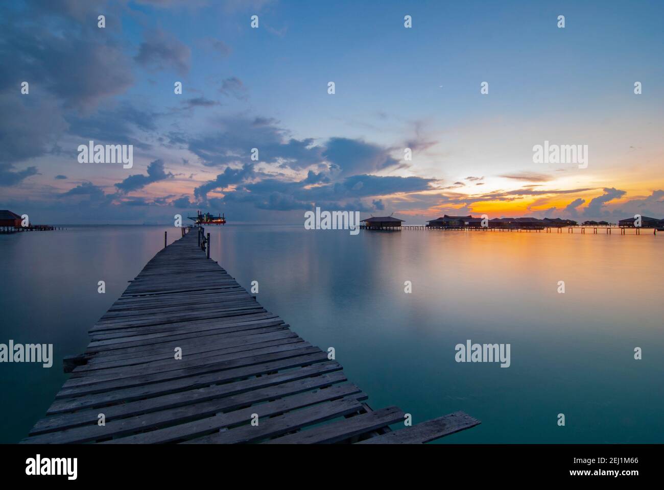 Tramonto sull'isola di Mabul con molo in legno, acqua setosa e casa galleggiante. Foto Stock