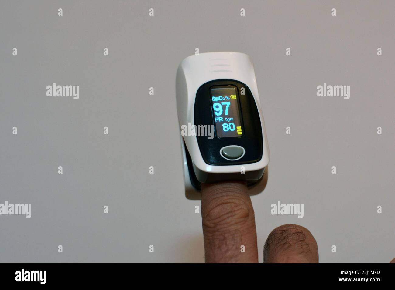 pulsossimetro fingertip collegato al dito indice di un giovane che misura la saturazione di ossigeno nel sangue e nel cuore tasso Foto Stock