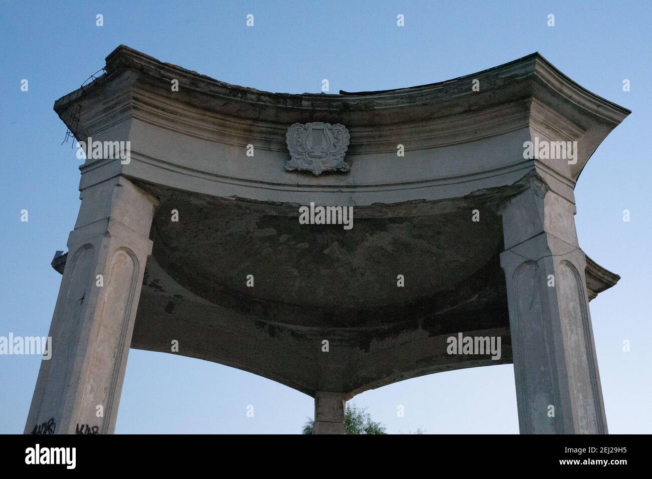 La cima del gazebo in pietra sbucciata con l'emblema lira al complesso di intrattenimento Lacul Morii a Bucarest. Romania Foto Stock