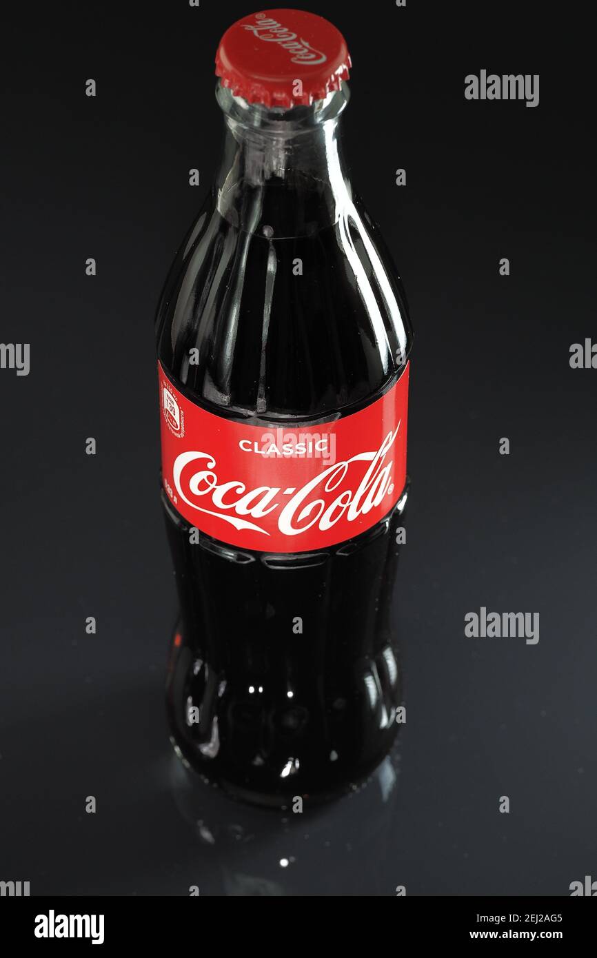 Coca cola. Una classica bottiglia di Coca Cola in vetro con coperchio rosso, isolata su fondo nero. Foto Stock