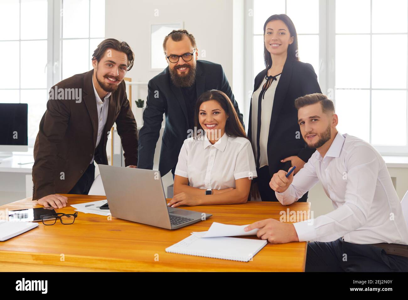 Ritratto di gruppo di felici e sorridenti uomini d'affari vicino al computer portatile nell'ufficio del business center. Foto Stock