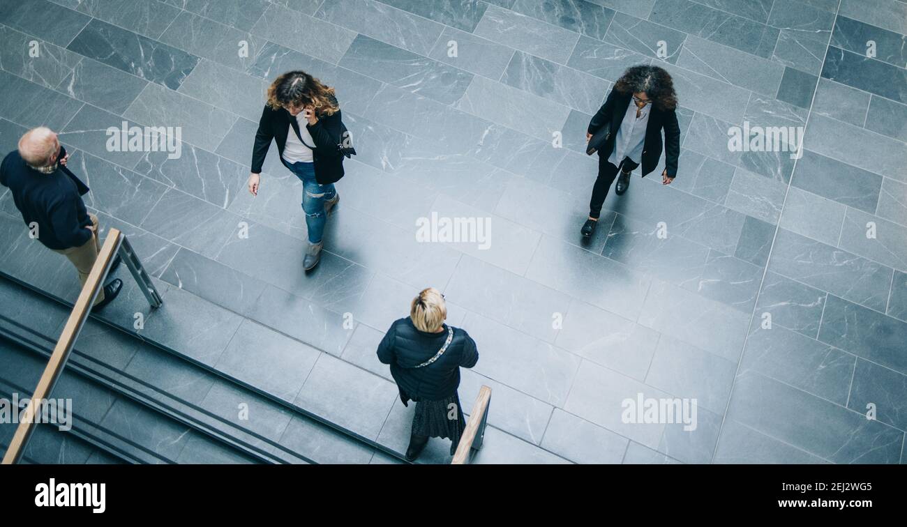 Vista ad alto angolo dei dirigenti aziendali che attraversano la hall del moderno edificio per uffici. gli uomini d'affari si spostano nel corridoio dell'ufficio. Foto Stock