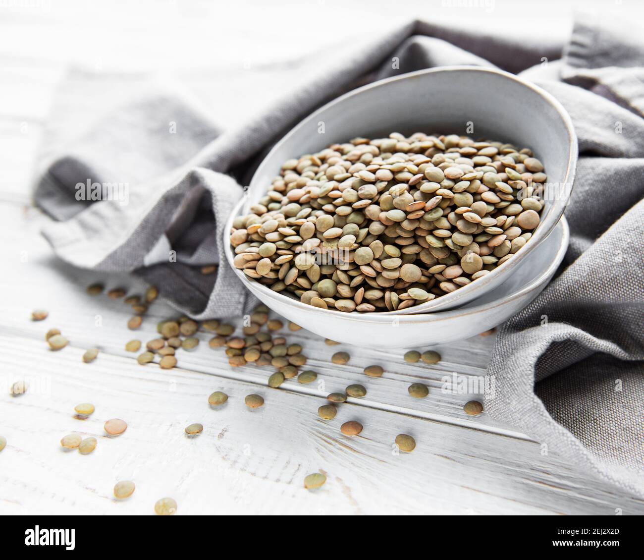 Pila di lenticchie grezze in una ciotola su legno bianco sfondo Foto Stock