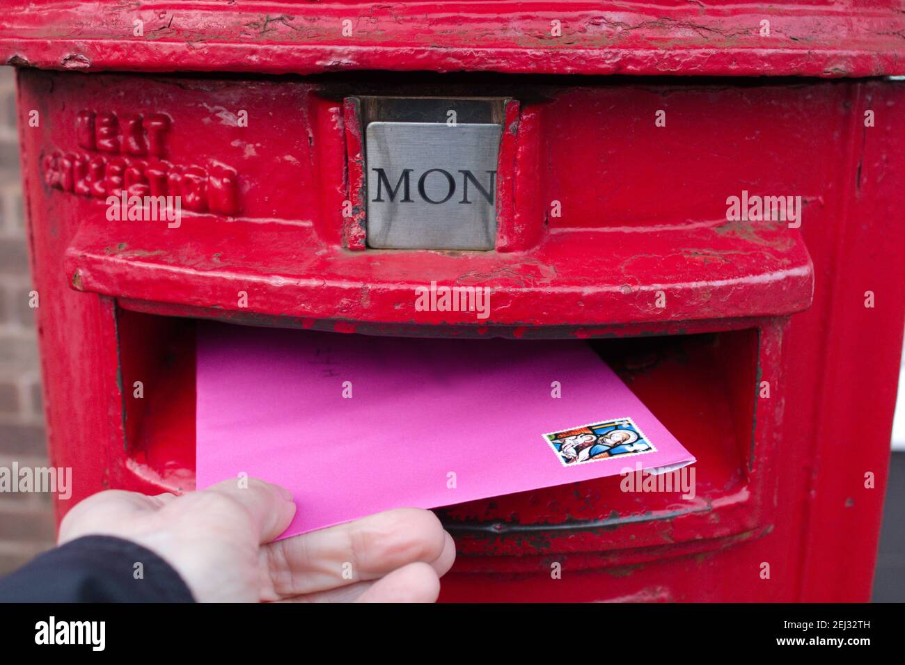 Invio di una lettera in un concetto di casella postale, casella postale del Regno Unito e busta rosa Foto Stock