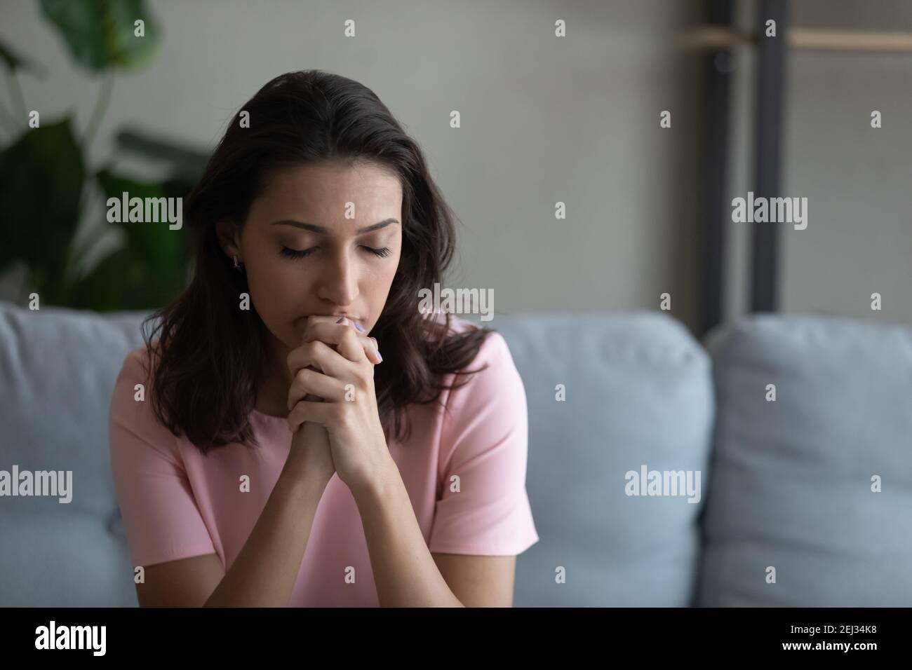 Preoccupata giovane donna araba che prega dio cercando di concentrarsi Foto Stock