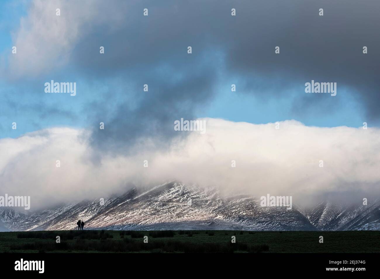 Splendida immagine paesaggistica della catena montuosa innevata di Skiddaw Lake District in inverno con nuvole di basso livello intorno alle vette Foto Stock