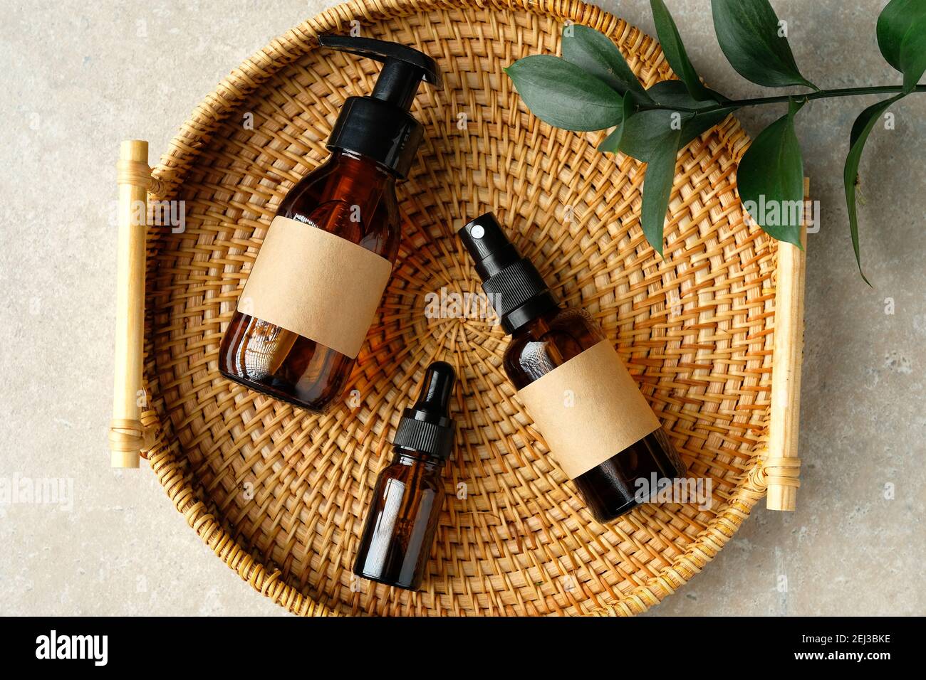 Bottiglie cosmetiche in vetro ambrato in contenitore di rattan su tavolo in bagno. PRODOTTI DI bellezza naturali biologici PER l'igiene personale, prodotti cosmetici da toletta Foto Stock