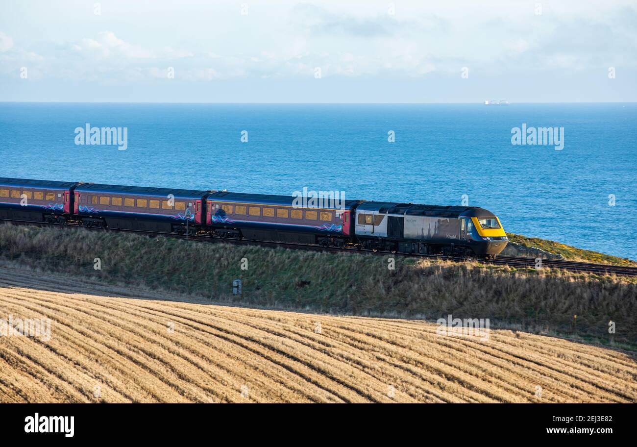 Un treno passeggeri su una linea ferroviaria a lato del mare In Scozia nel Regno Unito Foto Stock