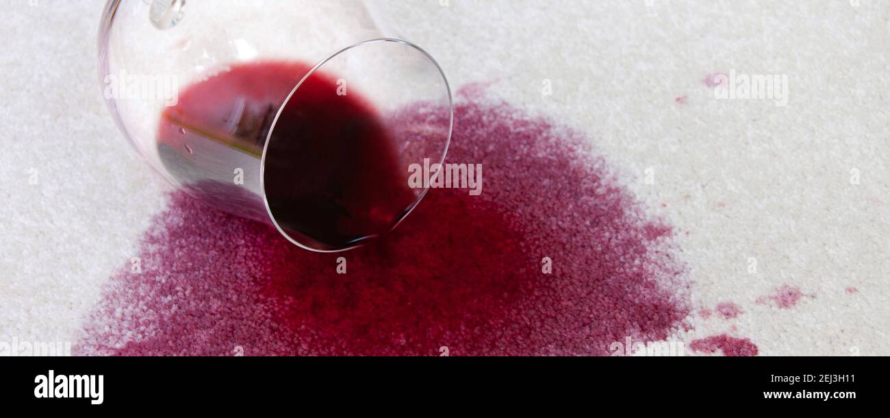 Umgestoßenes Weinglas mit Rotwein auf Teppich Foto Stock